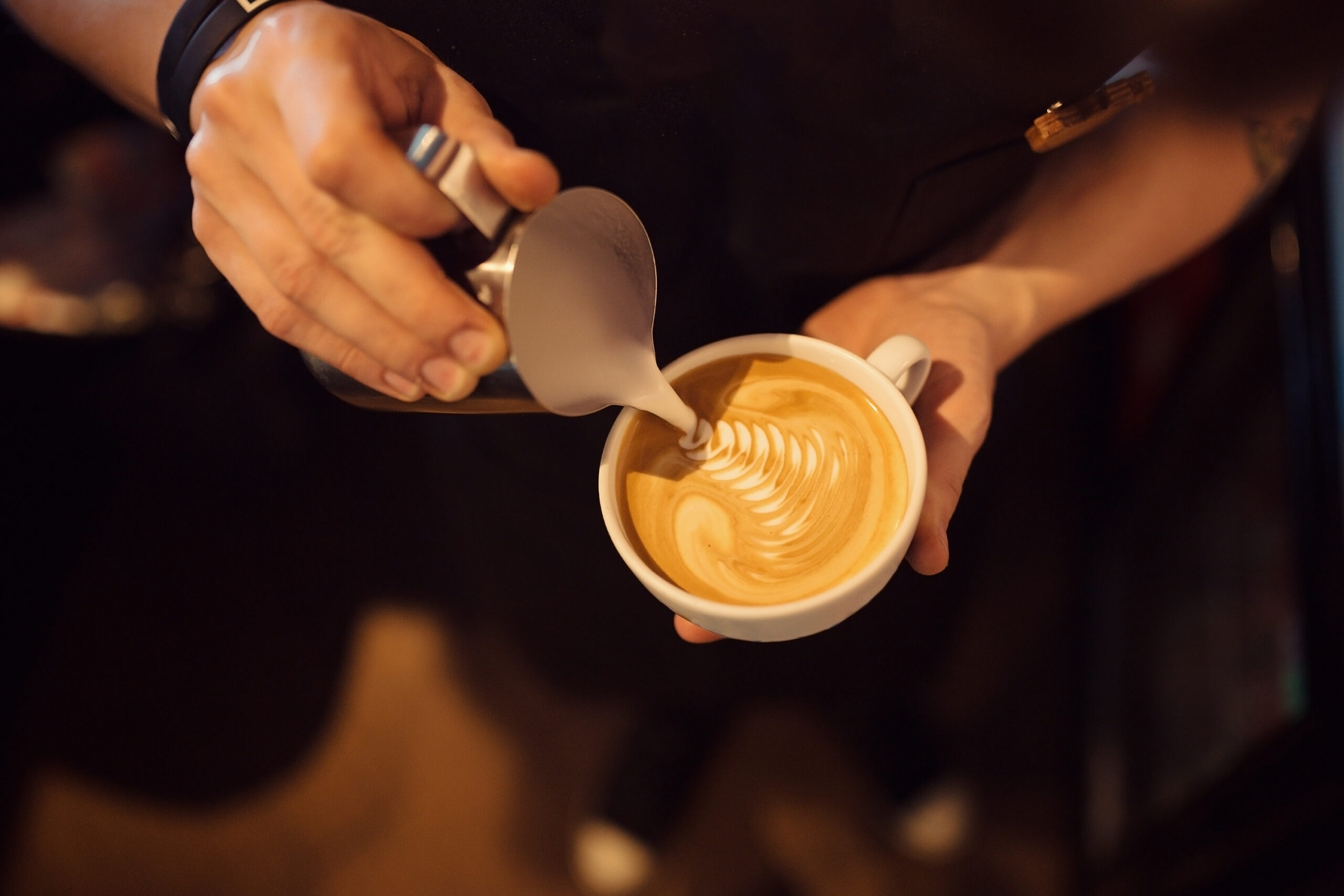 Barista servant un café latte de Cafés T'heim avec du latte art