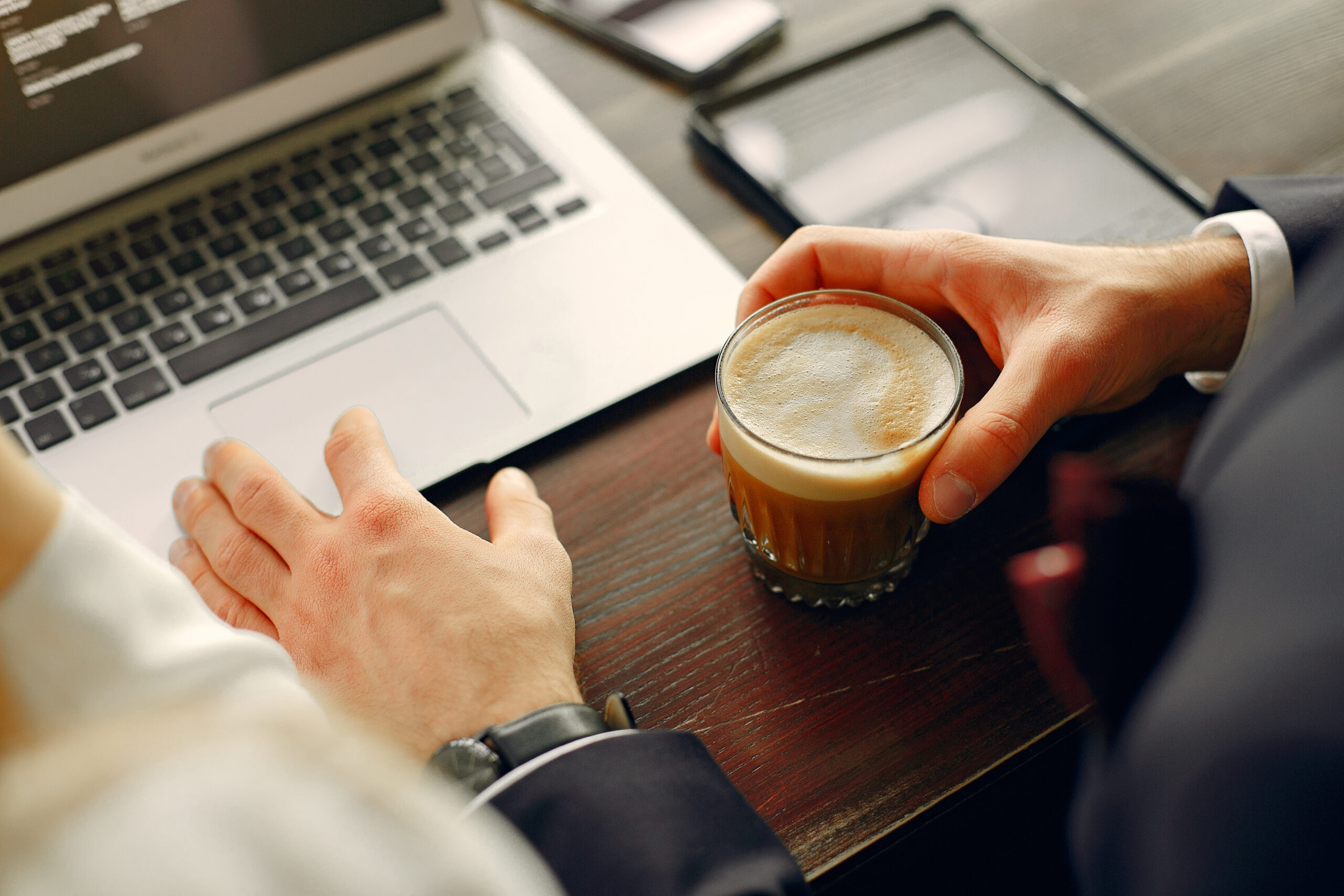 Pourquoi choisir Cafés T'HEIM pour votre entreprise ? Homme tenant un café devant un ordinateur